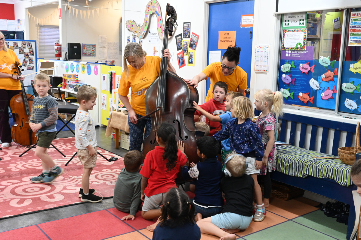 Marian and Jonny holding Double Bass with children around